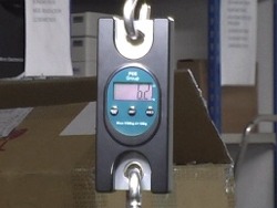 Display della bilancia per appendere PCE-HS 50 mentre sta misurando il peso di un pacco.